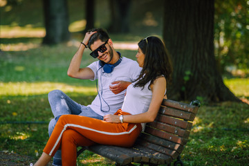 A pair of young people met in the park. Lovers are sitting on a bench