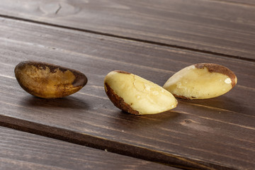 Group of three whole fresh unshelled brazil nut on brown wood
