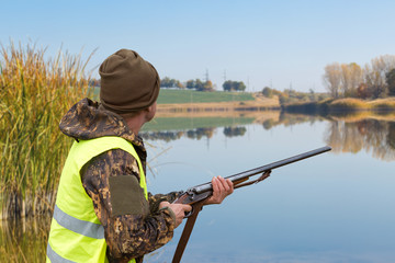 Hunter with a german drathaar and spaniel, pigeon hunting with dogs against the backdrop of a beautiful evening lake.
