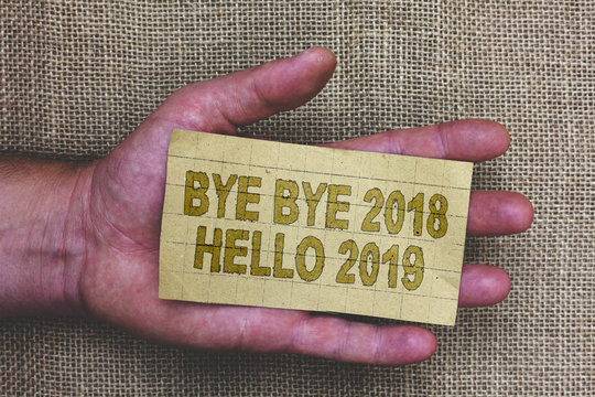 Conceptual hand writing showing Bye Bye 2018 Hello 2019. Business photo showcasing Starting new year Motivational message 2018 is over Thick gray paper with words human hands jute sack background