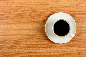 white ceramic coffee cup on wooden desk. - blank space for advertising text.