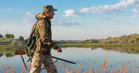 Hunter with a german drathaar and spaniel, pigeon hunting with dogs against the backdrop of a beautiful evening lake.	