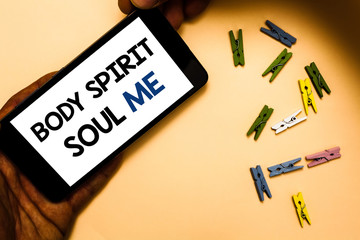 Conceptual hand writing showing Body Spirit Soul Me. Business photo text Personal Balance Therapy Conciousness state of mind Hand holding phone with letters and paperclip peach color ground