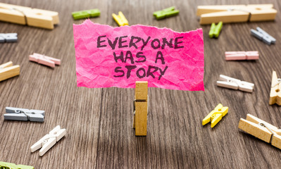 Conceptual hand writing showing Everyone Has A Story. Business photo showcasing Background storytelling telling your memories tales Paperclip hold pink note with texts many clips wooden floor