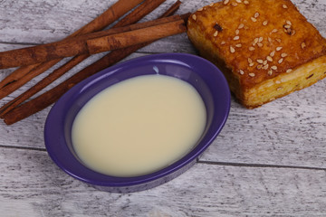 Condenced milk in the bowl with sinnamon and pastry