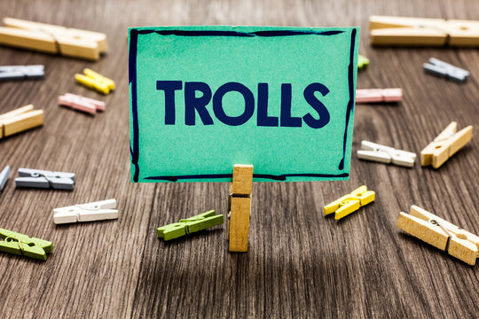 Text sign showing Trolls. Conceptual photo Online troublemakers posting provocative inflammatory messages Random clips art work board creative nice paperclips wood grey shadow