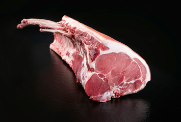 Dry aged Tomahawk Schweine Steak natur am Stück als closeup angeboten auf schwarzen Hintergrund...