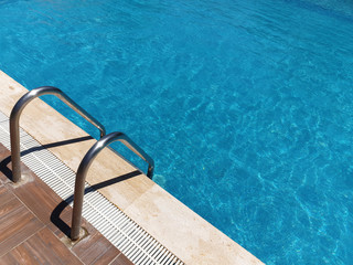 Iron ladder in the blue swimming pool