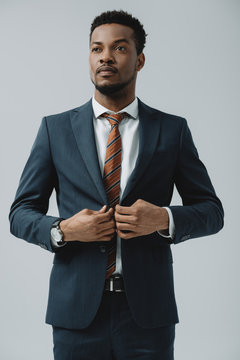 handsome african american man touching formal wear isolated on grey