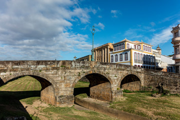 Fototapeta na wymiar Bridge over river with green grass and old buildings of the city hall of the historic city of Sao Joao del Rey in the state of Minas Gerais, Brazil