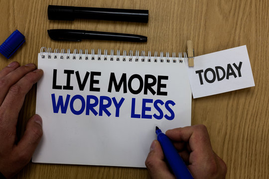 Word writing text Live More Worry Less. Business concept for Have a good attitude motivation be careless enjoy life Hand hold pen notepad with words paperclip grip note paper woody base black pen