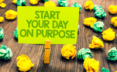 Fototapeta premium Handwriting text Start Your Day On Purpose. Concept meaning Have clean ideas of what you are going to do Paperclip retain written words yellow paper paper lobs laid on wooden floor