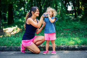 mother gives a little girl to drink water