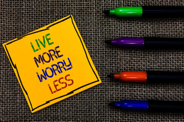 Conceptual hand writing showing Live More Worry Less. Business photo text Have a good attitude motivation be careless enjoy life Written on black lined yellow transverse note pen jute ground