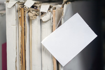Close-up stack of cardboard-wrapped furniture facades with a white sign for inscription, selective focus