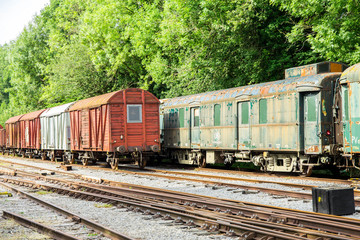 Fototapeta na wymiar Various rusted wagons and train on the tracks
