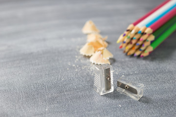 Pencil sharpener and pencil shavings with small particles on blackboard background. School supplies. Concept back to school