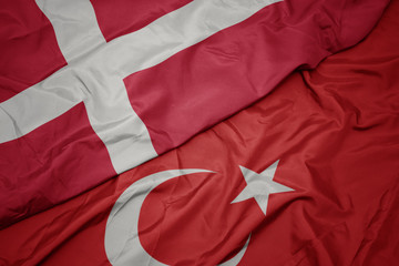 waving colorful flag of turkey and national flag of denmark.