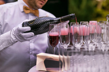 the waiter pours champagne into glasses for a party, red wine in glasses, champagne at a celebration