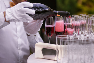 the waiter pours champagne into glasses for a party, red wine in glasses, champagne at a celebration