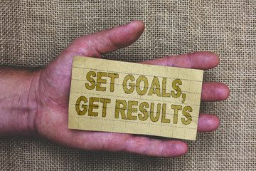 Conceptual hand writing showing Set Goals, Get Results. Business photo showcasing Establish objectives work for accomplish them Thick gray paper with words human hands jute sack background