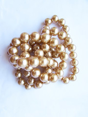 Beautiful mother-of-pearl light beige pastel large beads on a thread on a white fabric Isolated object.