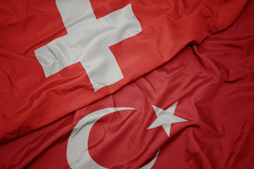 waving colorful flag of turkey and national flag of switzerland.