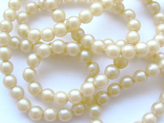 Delicate light natural small pearl long beads on a white background.