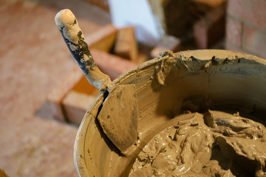 Builder builds a brick stove, builder tools. Trowel with a solution in a bucket