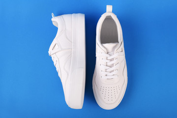 A pair of white sneakers on the blue background