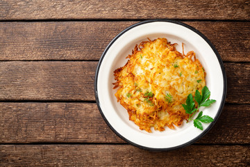 Potato pancakes or latkes or draniki in plate on dark wooden table. Top view. Copy space.