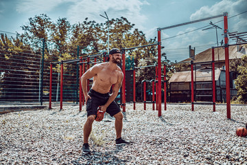 Athletic man working out with a kettlebell at street gym yard. Strength and motivation. Outdoor workout. Exercise for shoulders.