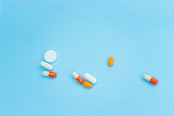 Falling colorful medical pills on blue background