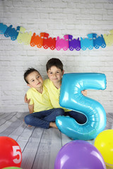 niños felices sujetando un globo con el número 5 