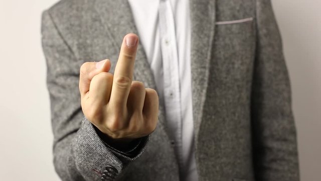 Solid caucasian man in gray jacket and speckled shirt on white background showing his middle finger. disrespectful flip off finger sign, gesture to ill-wishers and envious