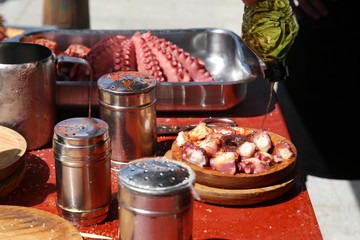 preparación de pulpo a la gallega, con aceire, pimentón y sal