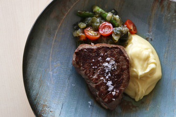 delicioso medallón de carne con verduras y puré de patata en un plato azul