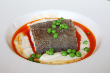 bacalao con guisantes y puré de patata en plato hondo
