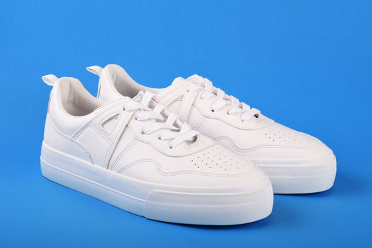 A pair of white sneakers on the blue background