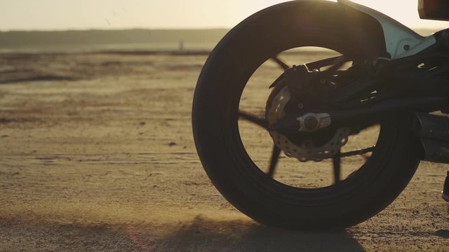 Motorcyclist doing tire burnout in the desert, slow motion. Professional motorcyclist drift and turns on a motorcycle on the ground, a biker does a trick on a motorcycle