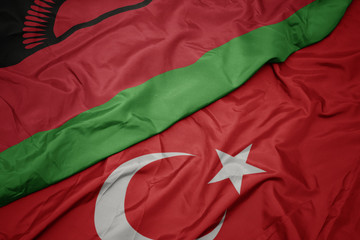 waving colorful flag of turkey and national flag of malawi.