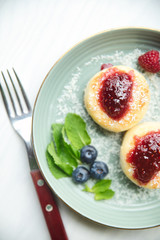 Cheesecakes with raspberry jam, berries and mint leaves served on a white background