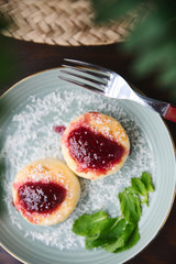 Cheesecakes with raspberry jam, berries and mint leaves served on a dark background