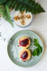 Cheesecakes with raspberry jam, berries and mint leaves served with a cup of latte