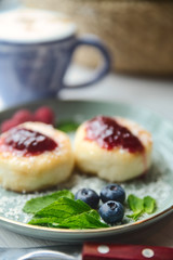 Cheesecakes with raspberry jam, berries and mint leaves served with a cup of latte