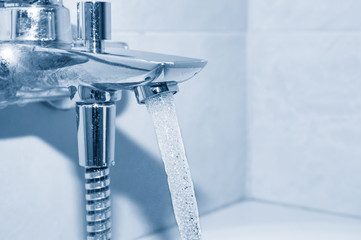 Flowing water from tap on blue background