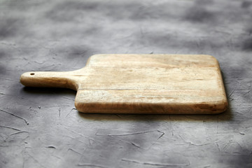 Empty cutting board from pine wood on  stone table, grey background, side view