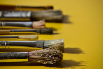 Artists paint brushes with selective focus on yellow background