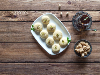 Peda (Indian sweet), Milk Fudge with tea cup in a dark wooden table. Top view
