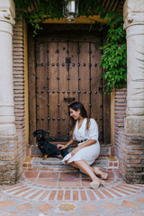 cute small sausage dog sitting outdoors with her owner at home. Woman cuddling her dog. Love for animals concept